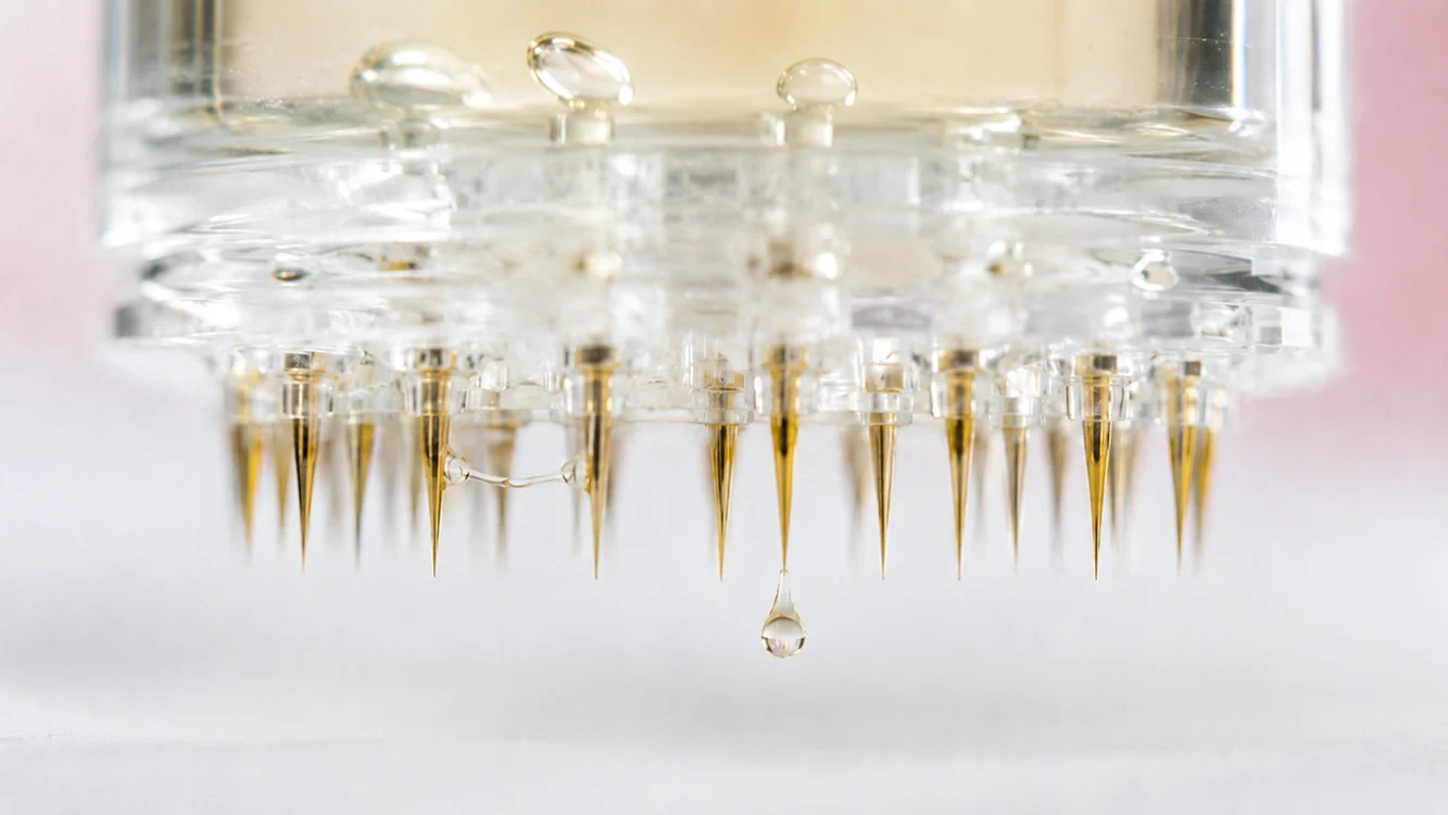 Macro view of a micro-infusion stamp head with ultra-fine needle tips carrying a bead of serum